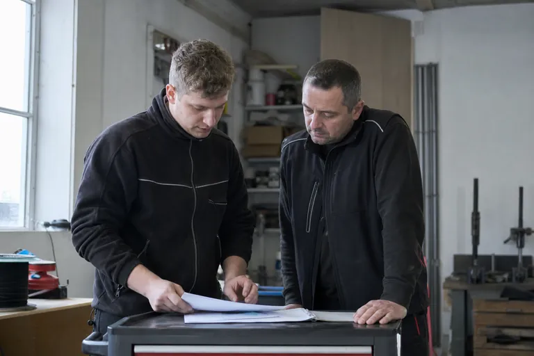 Elektrofachkraft und Betriebsleiter besprechen Zuständigkeiten bei einer Geräteliste